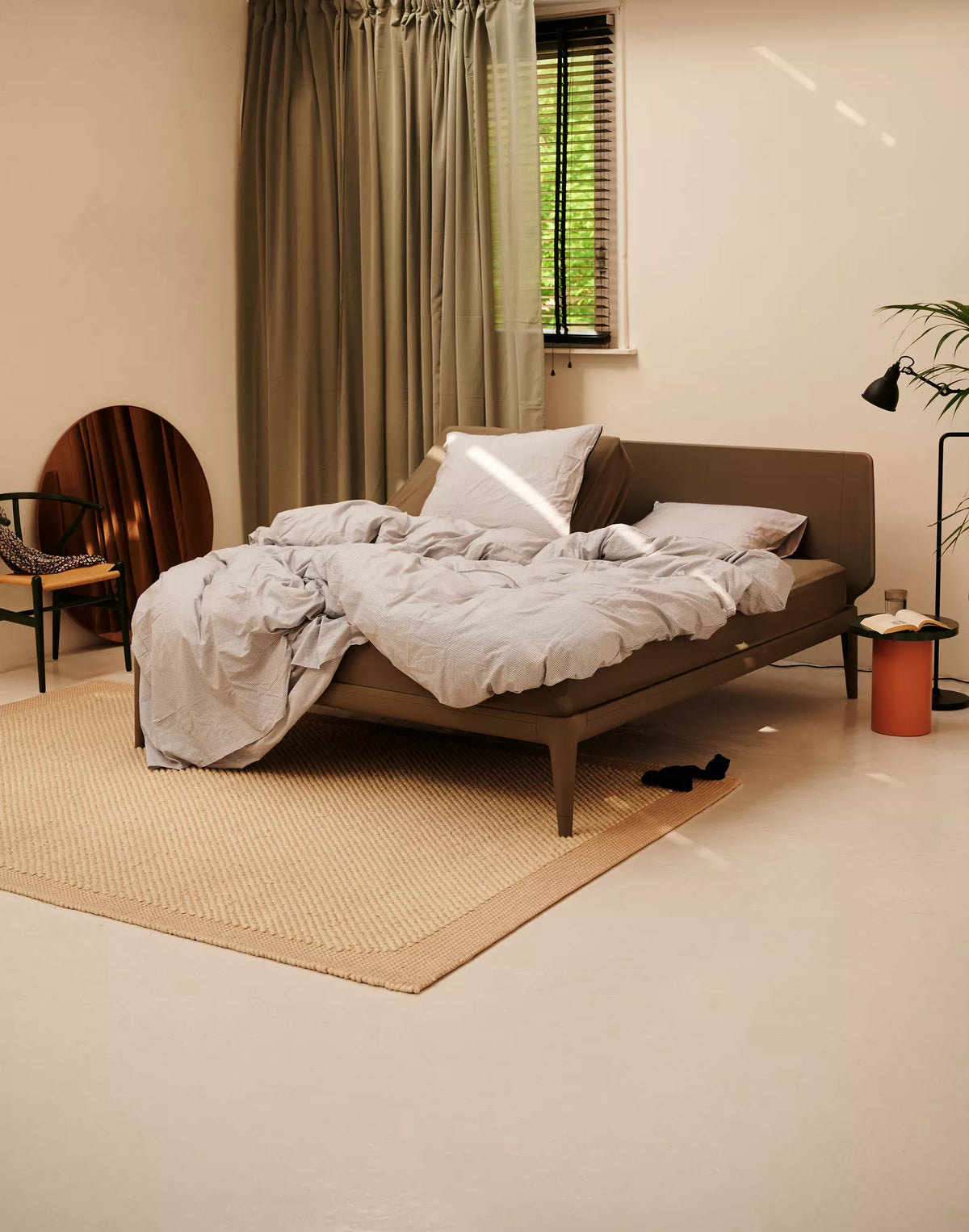 Auping Essential bed in Warm Grey in een slaapkamer met groene gordijnen en sisal vloerkleed