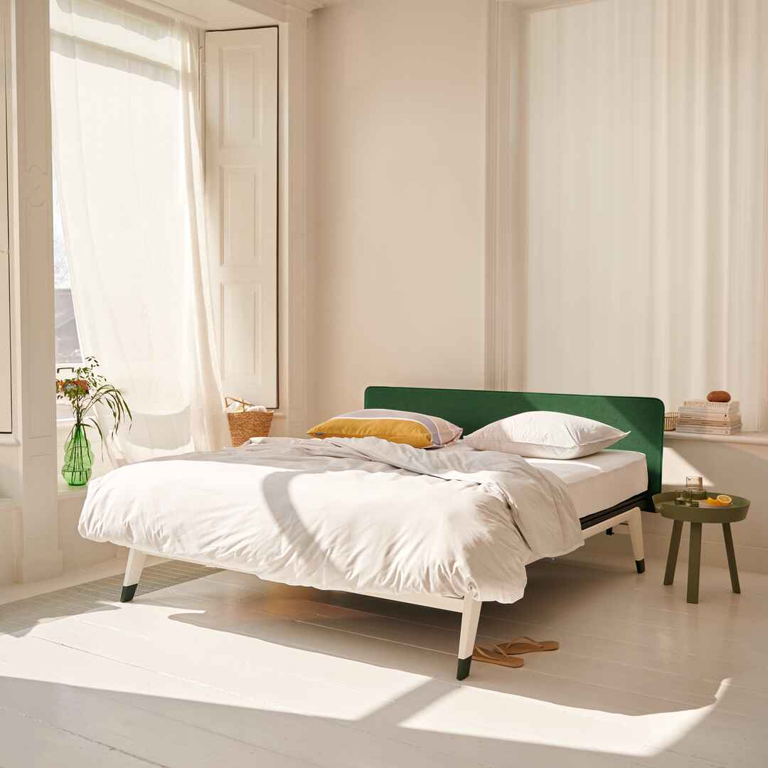 Auping Original met groen Straight hoofdbord en lichte bedombouw in zonnige slaapkamer