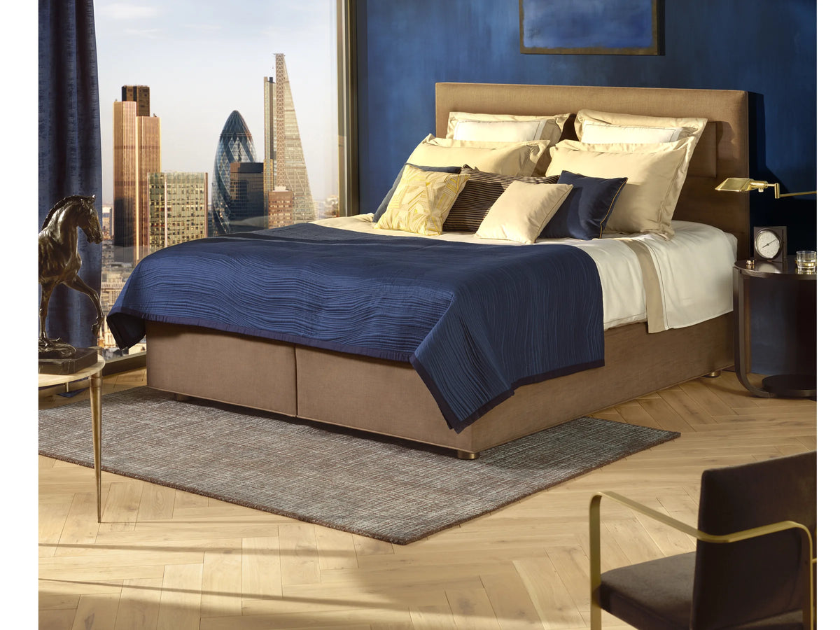 Opgemaakt bed met Vispring Marquess Superb matras, kussens en donkerblauwe sprei